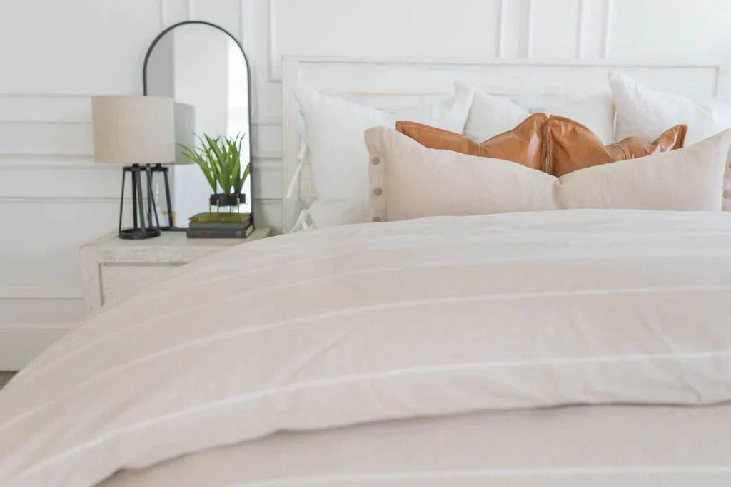
      A bed made with zipper bedding and a striped duvet folded at the foot of the bed
    