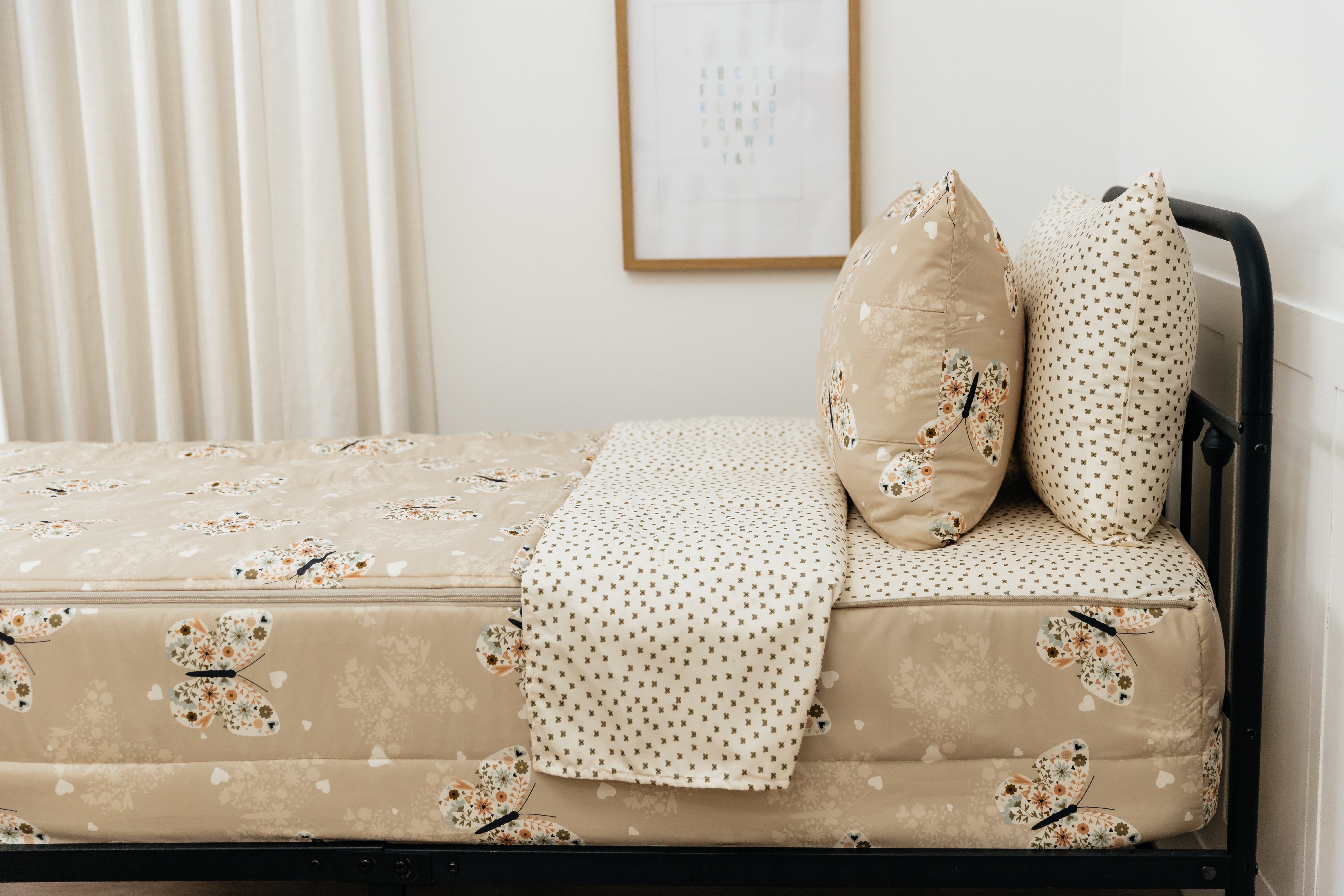 A bed made with butterfly printed zipper bedding, showcasing the pillowcase and sham and the top of the bedding turned down to show the inside lining.