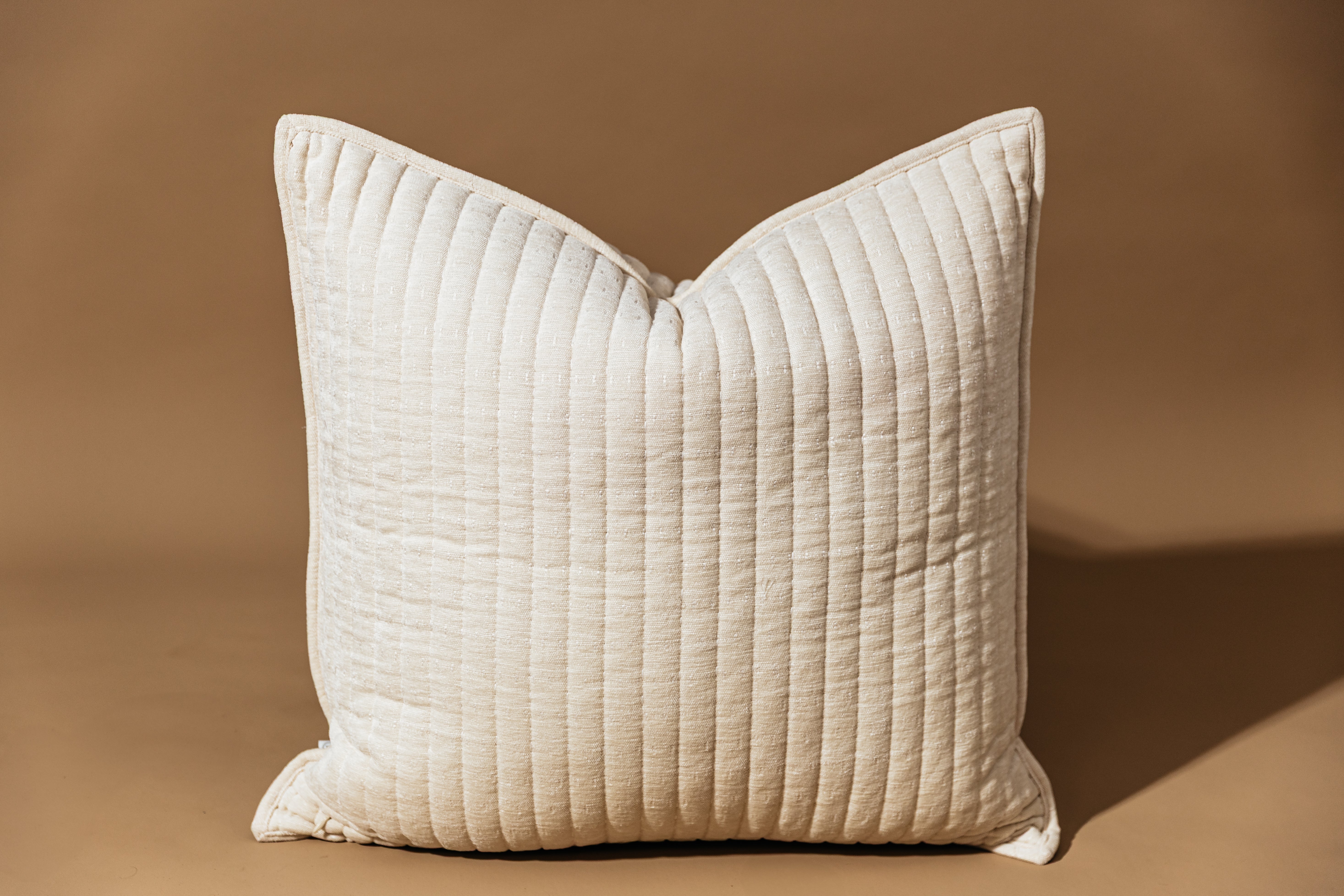 Cream textured pillow on tan background