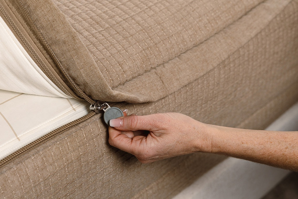 Close up photo of zipper being pulled on tan woven zipper bedding.