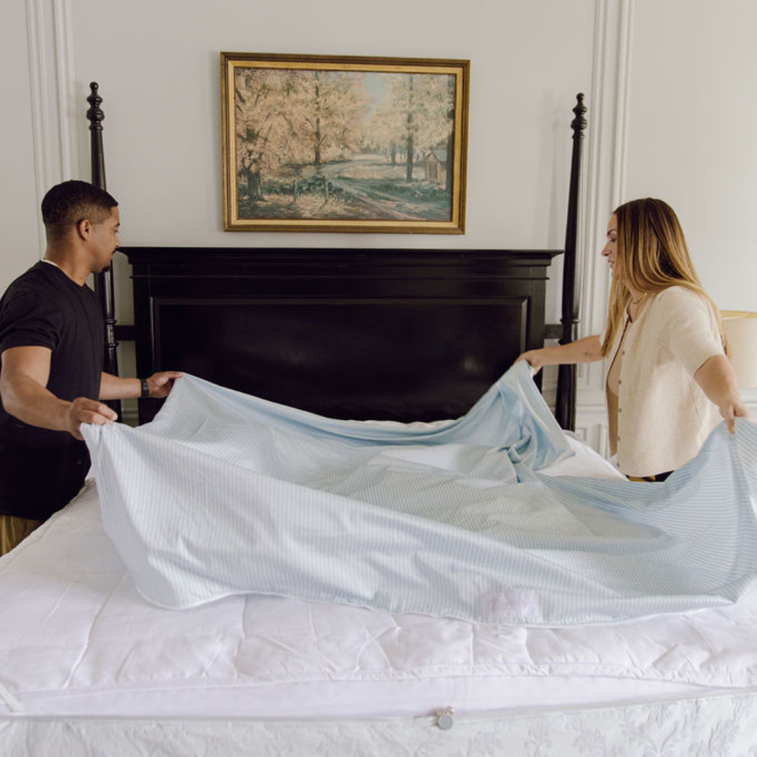 A couple arranging the detachable ZipBase fitted sheet top on their Bed-dys set.